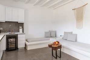 A modern kitchen with white cabinets, a built-in wine cooler, and a seating area with a bench and cushions.