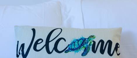 Un cojín con un mensaje de bienvenida y un diseño de tortuga.