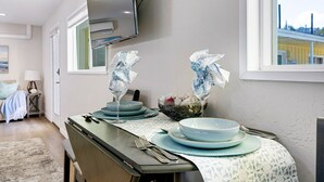 Comedor con una mesa dispuesta para dos personas, con vajilla de diseño azul y blanco y un florero con flores.
