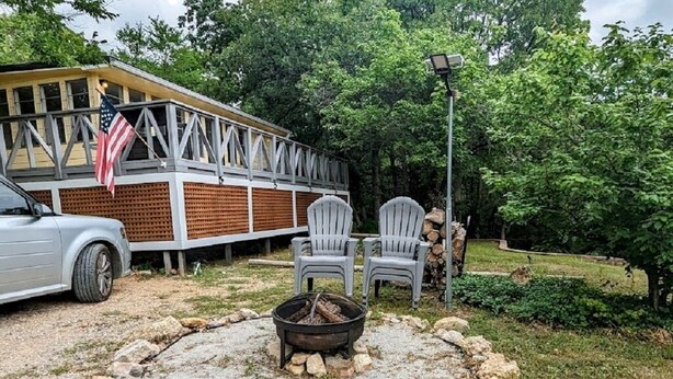 Een rustieke buitenruimte met Adirondack stoelen, een vuurkorf en een houten terras met een Amerikaanse vlag.
