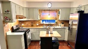 Cocina compacta con una isla central, estufa, refrigerador y ventana con vistas.