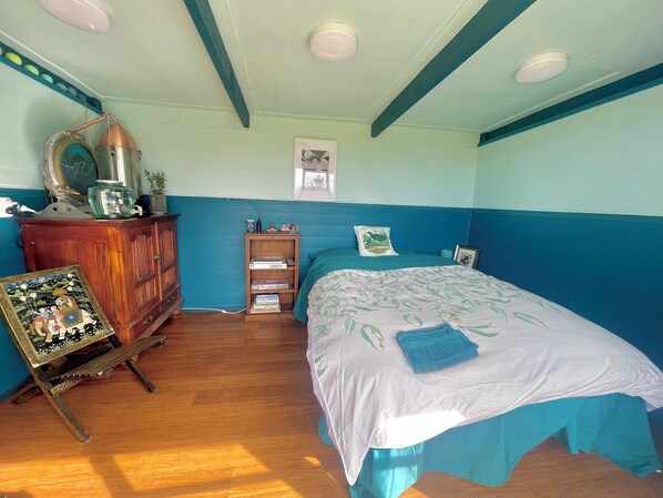 A room with a bed, a wooden cabinet, a shelf with books, and a framed picture on the wall.