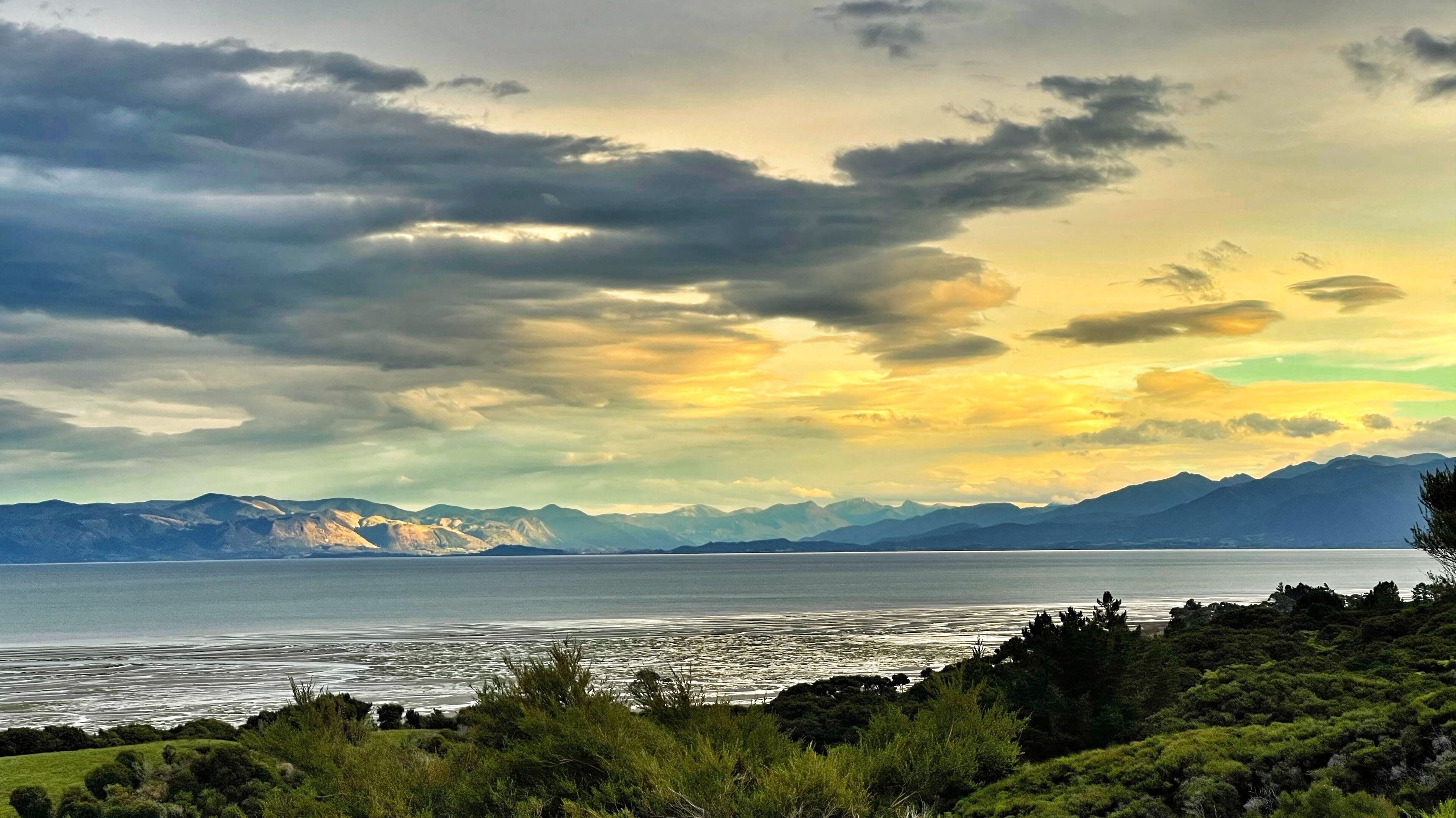 A coastal landscape with mountains in the background and a body of water in the foreground.