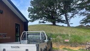 A Toyota pickup truck parked in front of a building with a 'PARKING' sign. - Maelstrom End - Eco Farm Stay Cabin (Pūponga)