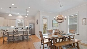 A spacious kitchen with a central island, wooden chairs, and a chandelier. - 6-Seater LSV, 4 Bikes, Highland Park Stunner! Community Pool & Hot Tub! (Santa Rosa Beach)