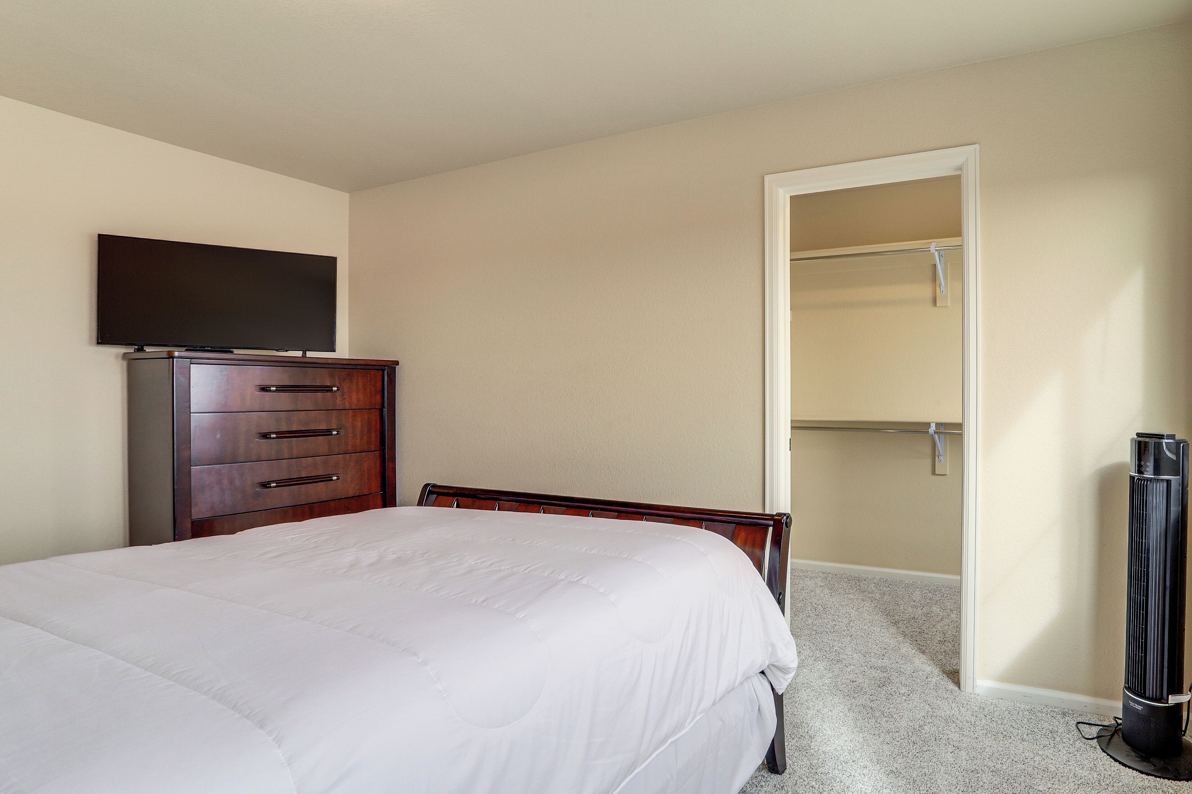 A bedroom with a bed, a dresser, a television, and a closet.