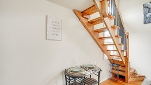 A dining area with a wooden staircase, a framed inspirational quote on the wall, and a small table set with plates and glasses. - Pacheco/Martinez Studio: 22 Mi to Dtwn Oakland! (Pacheco)