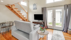 A living room with a grey sofa, wooden staircase, a flat-screen TV, and a dining table with glasses. - Pacheco/Martinez Studio: 22 Mi to Dtwn Oakland! (Pacheco)