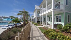 A beachfront hotel with a pool, lounge chairs, and a covered walkway.