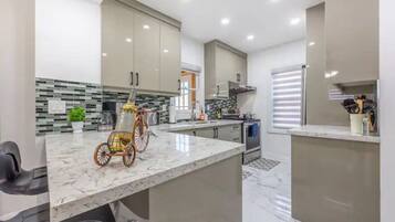A modern kitchen with a marble countertop, stainless steel appliances, and a unique bicycle rack.