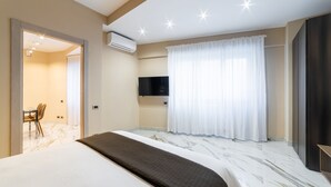 Hotelkamer met een bed, een aan de muur bevestigde televisie, een bureau met stoel, en een badkamer zichtbaar door een open deur.