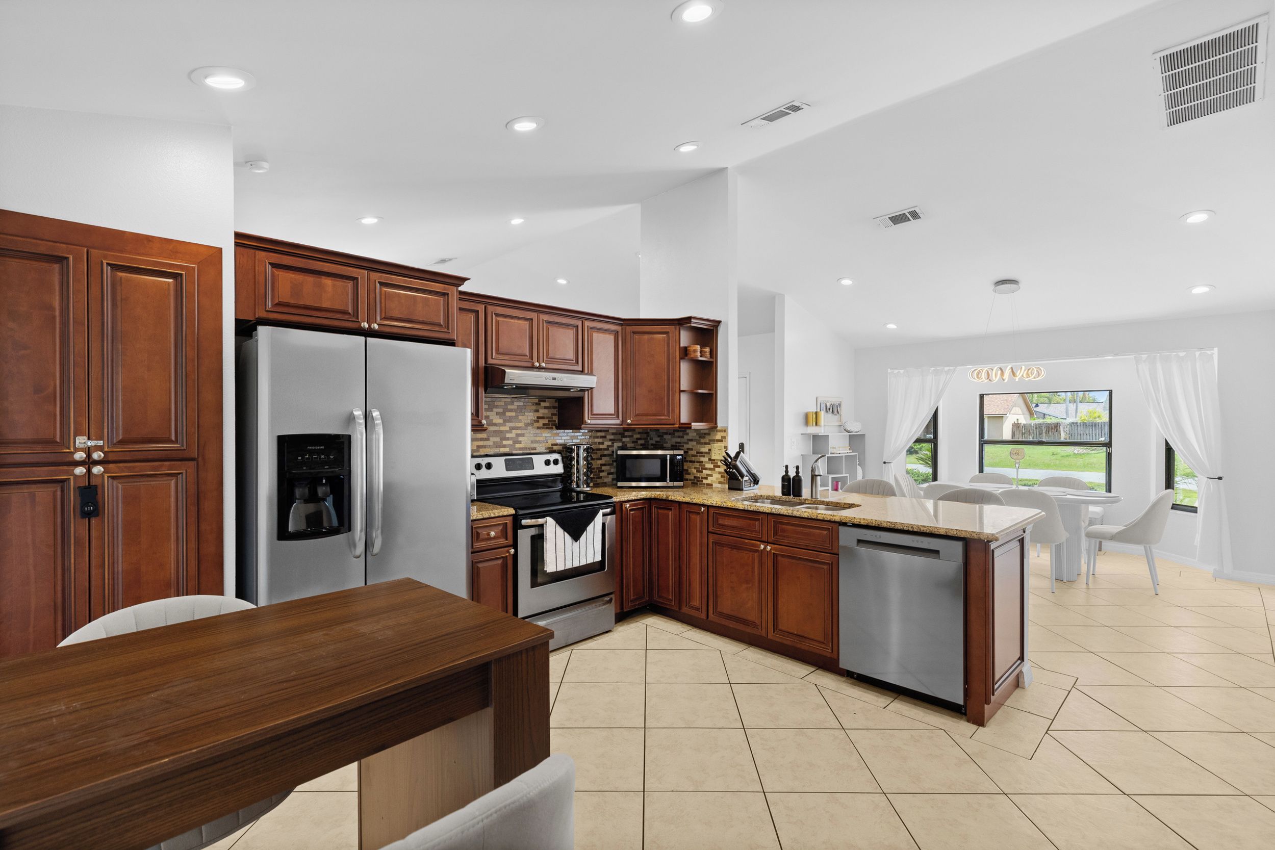A modern kitchen with stainless steel appliances, wooden cabinets, and a central island.