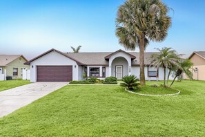 A single-story house with a garage, a front lawn, and a palm tree.