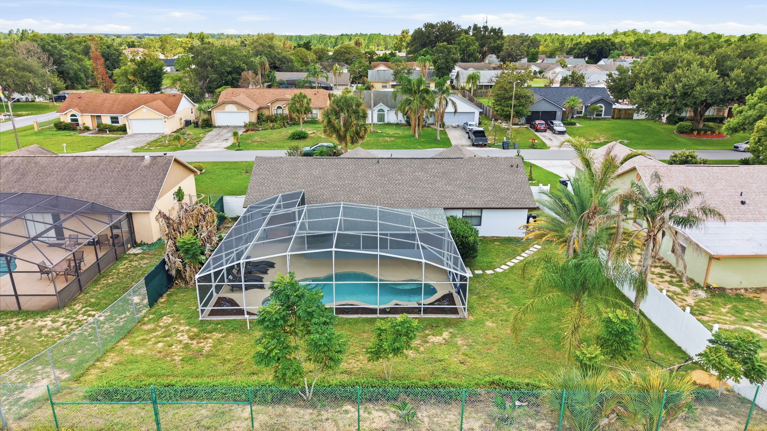 A residential area with houses, a swimming pool, and a fenced yard.