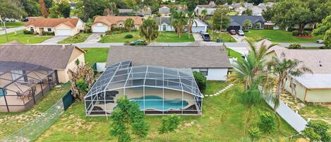 A residential area with houses, a swimming pool, and a fenced yard.