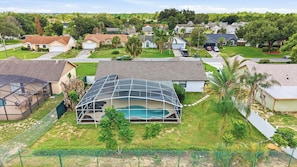 A residential area with houses, a swimming pool, and a fenced yard. - Sunshine Villa:3BR Home with Sparkling Heated Pool/Huge Backyard (Davenport)