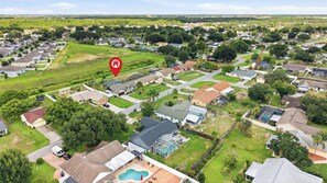 A residential area with houses, green lawns, and a swimming pool. - Sunshine Villa:3BR Home with Sparkling Heated Pool/Huge Backyard (Davenport)