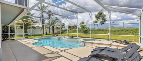 Un espace piscine extérieur doté d’une zone abritée, de chaises longues et offrant une vue sur le paysage environnant.