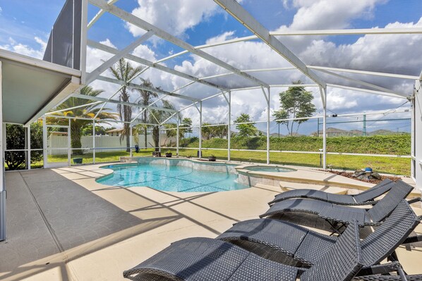 An outdoor swimming pool area with a covered section, lounge chairs, and a view of the surrounding landscape.
