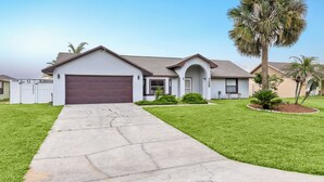 Une maison de plain-pied avec un garage, une allée et une pelouse bien entretenue.