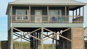 A two-story house with a balcony, wooden deck, and a metal roof.