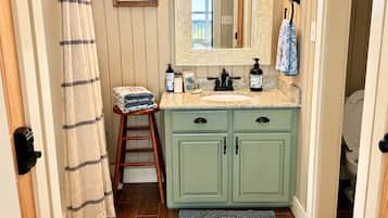 A bathroom with wooden panel walls, a vanity with a mirror, a sink, and a shower curtain.