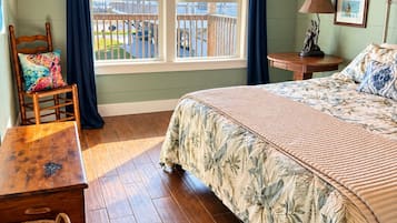 A bedroom with a bed, a chair, a table, a lamp, and two deer head wall decorations.