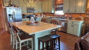 A spacious kitchen with a central island, wooden cabinets, and a chandelier.
