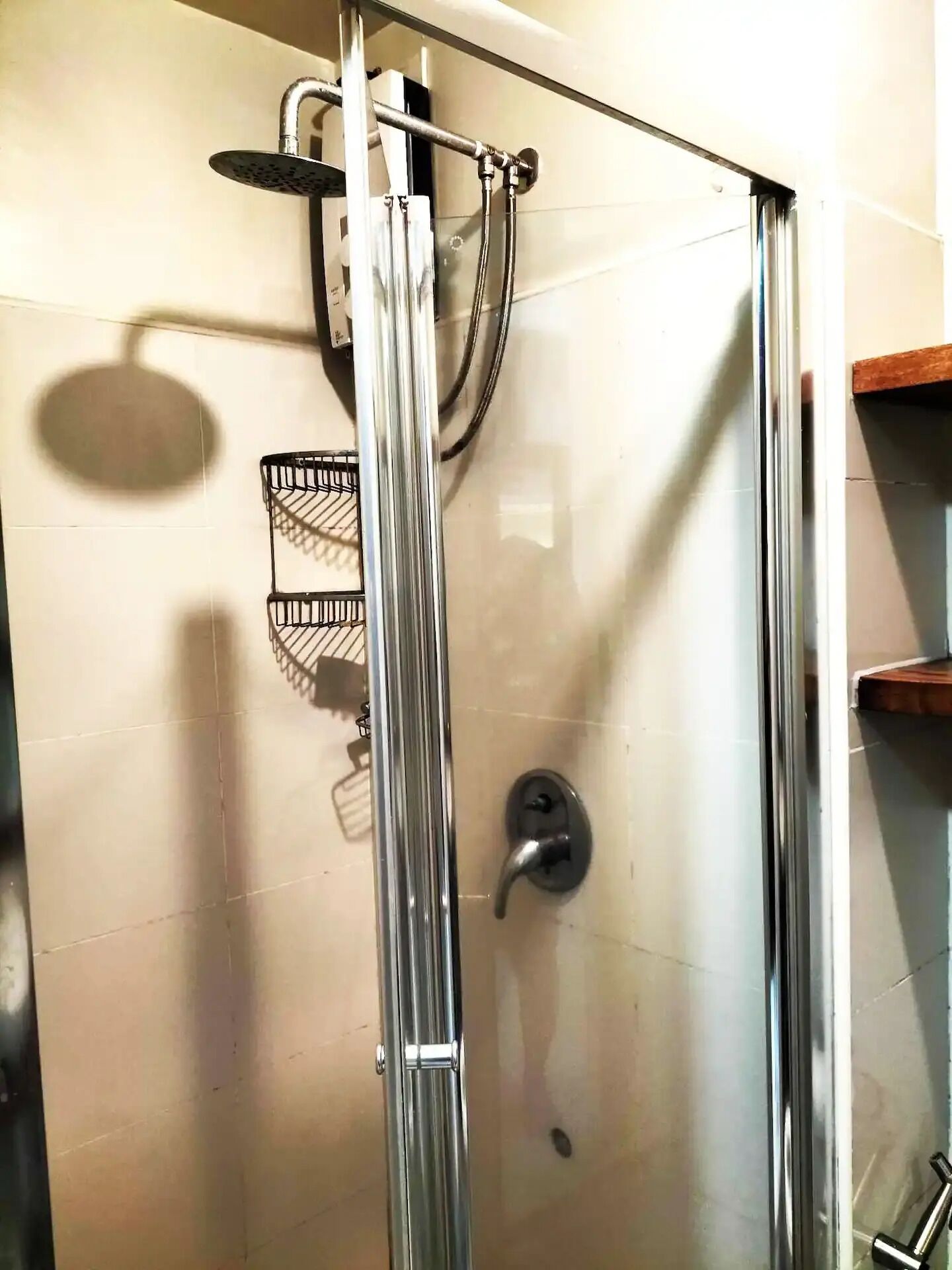 A glass-enclosed shower with a handheld showerhead and a handheld shower attachment.