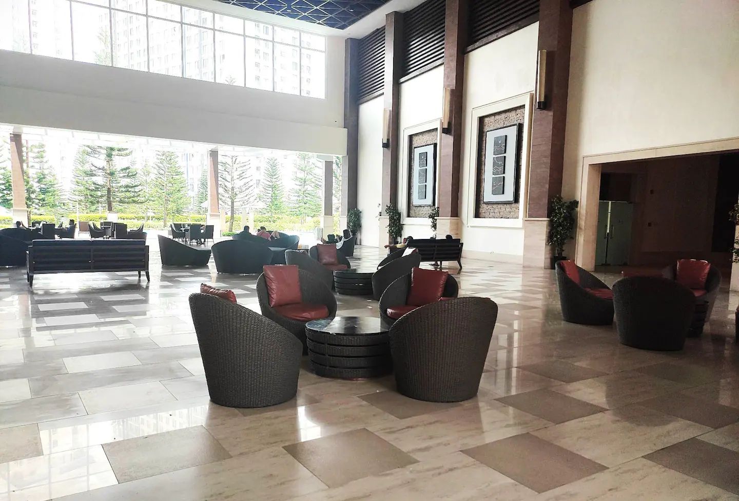 Eine großzügige Lobby mit hoher Decke, großen Fenstern und einer Mischung aus Sitzgelegenheiten, darunter Sofas und Sessel.