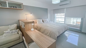 Ein modernes Schlafzimmer mit einem Bett, einem Schreibtisch, einem Stuhl und einem Nachttisch.