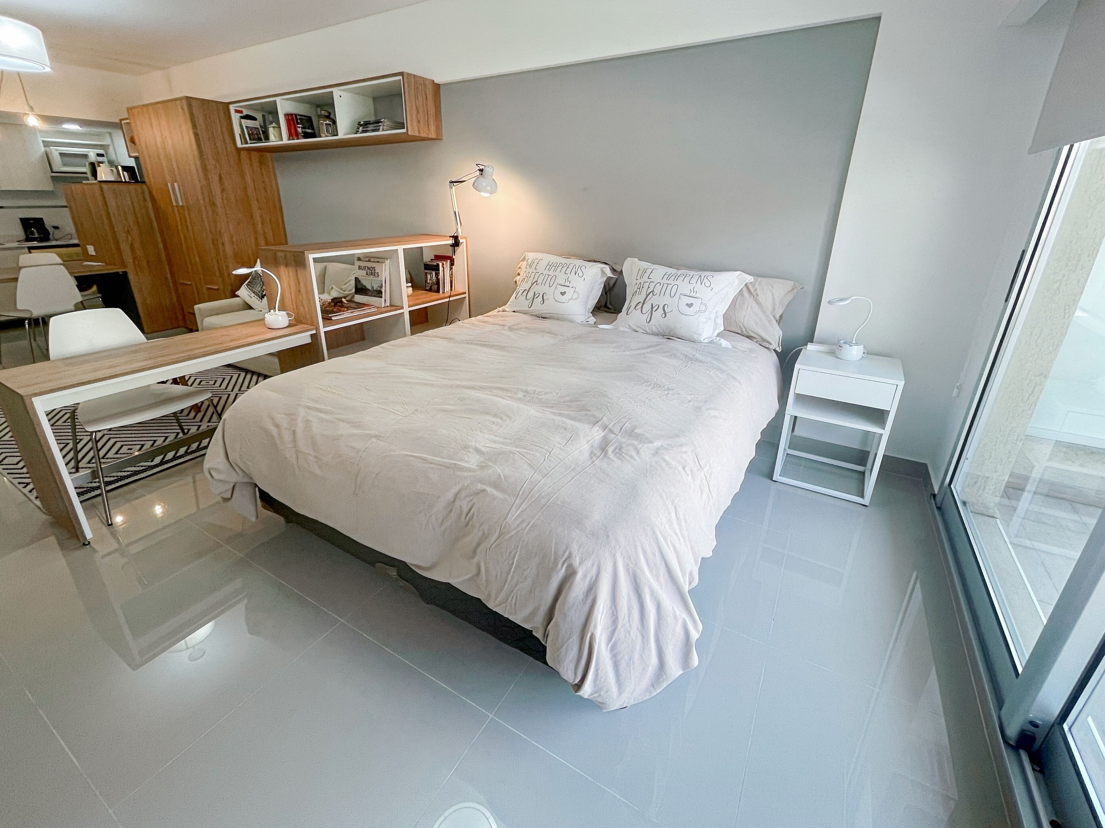 A modern bedroom with a large bed, a desk, and a wardrobe.