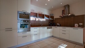 Eine moderne Küche mit Edelstahlgeräten, weißen Schränken und einer gefliesten Spritzschutzwand.