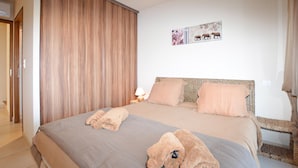 Ein Schlafzimmer mit einem großen Bett, zwei Kissen, einem Nachttisch mit Lampe und einem an der Wand hängenden Elefantenhänger.