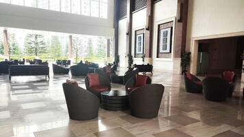 Un hall espacioso con muebles de mimbre modernos, ventanas amplias y un techo alto.