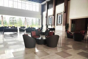 A spacious lobby with modern wicker furniture, large windows, and a high ceiling. - 838 Wind Residences Lake and Taal Volcano view (Tagaytay)