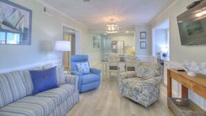 A living room with a sofa, armchair, and a dining area with a table and chairs.