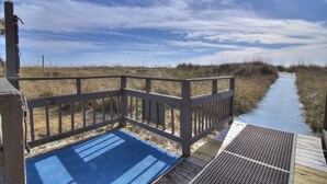 A wooden boardwalk leading to a beach area with a blue mat at the start.