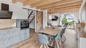 A modern kitchen with a built-in oven and a dining area with a wooden table and blue chairs.