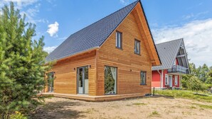 A modern wooden house with a steeply pitched roof, large windows, and a visible balcony.