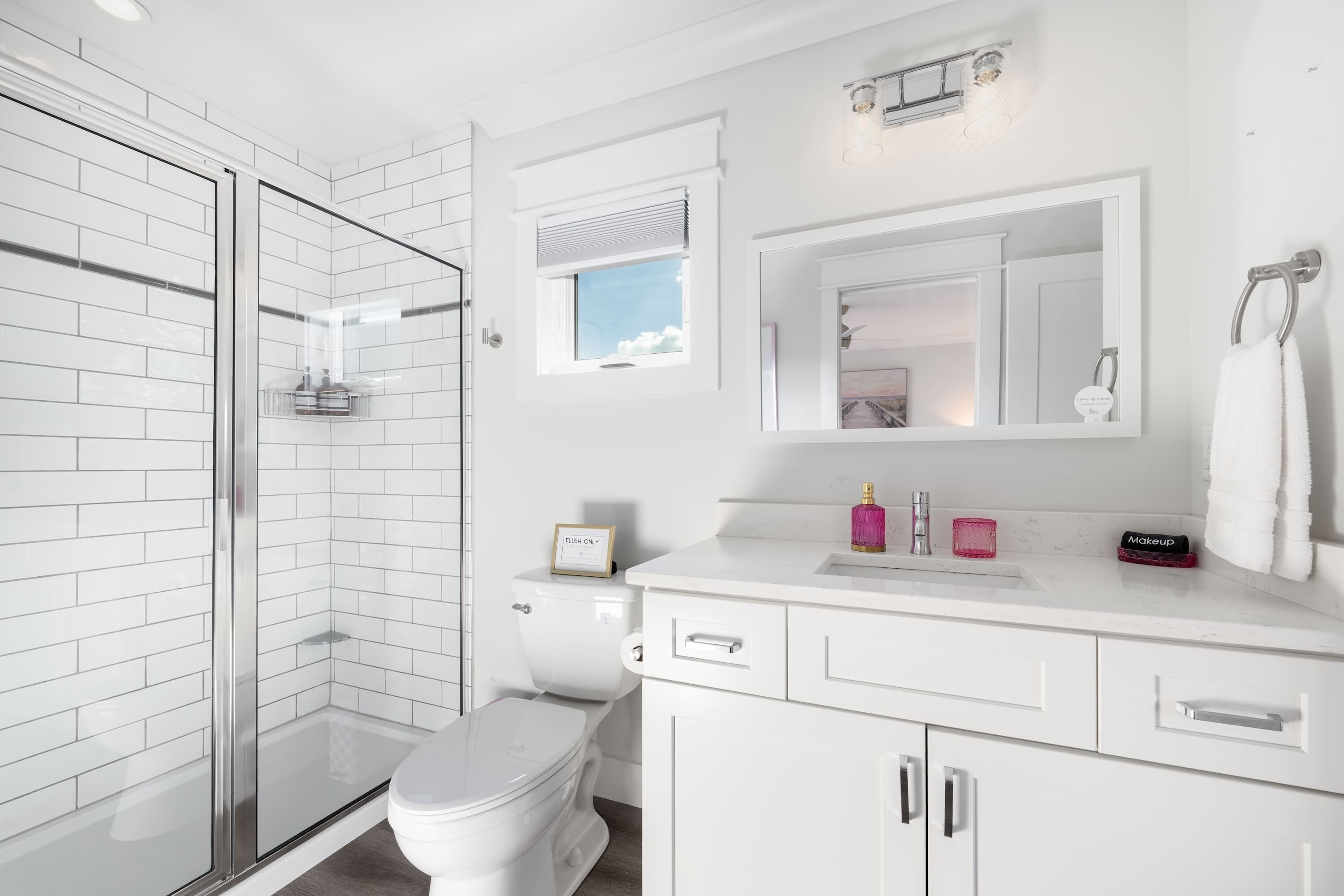 Une salle de bain moderne avec une douche à parois de verre, des toilettes, un lavabo avec un meuble-vasque et un miroir.