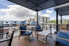 A balcony with seating, a view of buildings, and a cloudy sky. - Harmony at The Cove Riverwalk Villas (Wilmington)