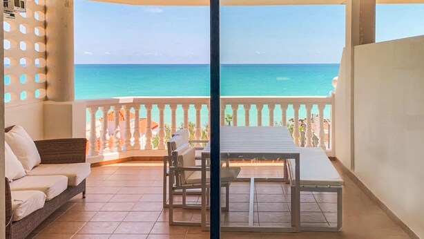 A balcony with a view of the ocean, a table, and two chairs. - 2 bedroom nice apartment in Moncofa (Moncofa)