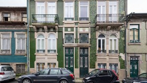 Une rangée d’immeubles à étages, aux façades vertes et beiges, agrémentés de balcons et de cadres de fenêtres décoratifs.