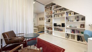Un salon moderne avec une grande bibliothèque, un canapé, une table basse et un tapis rouge.