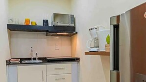 Eine kleine Küche mit Mikrowelle, Kaffeemaschine und Kühlschrank.