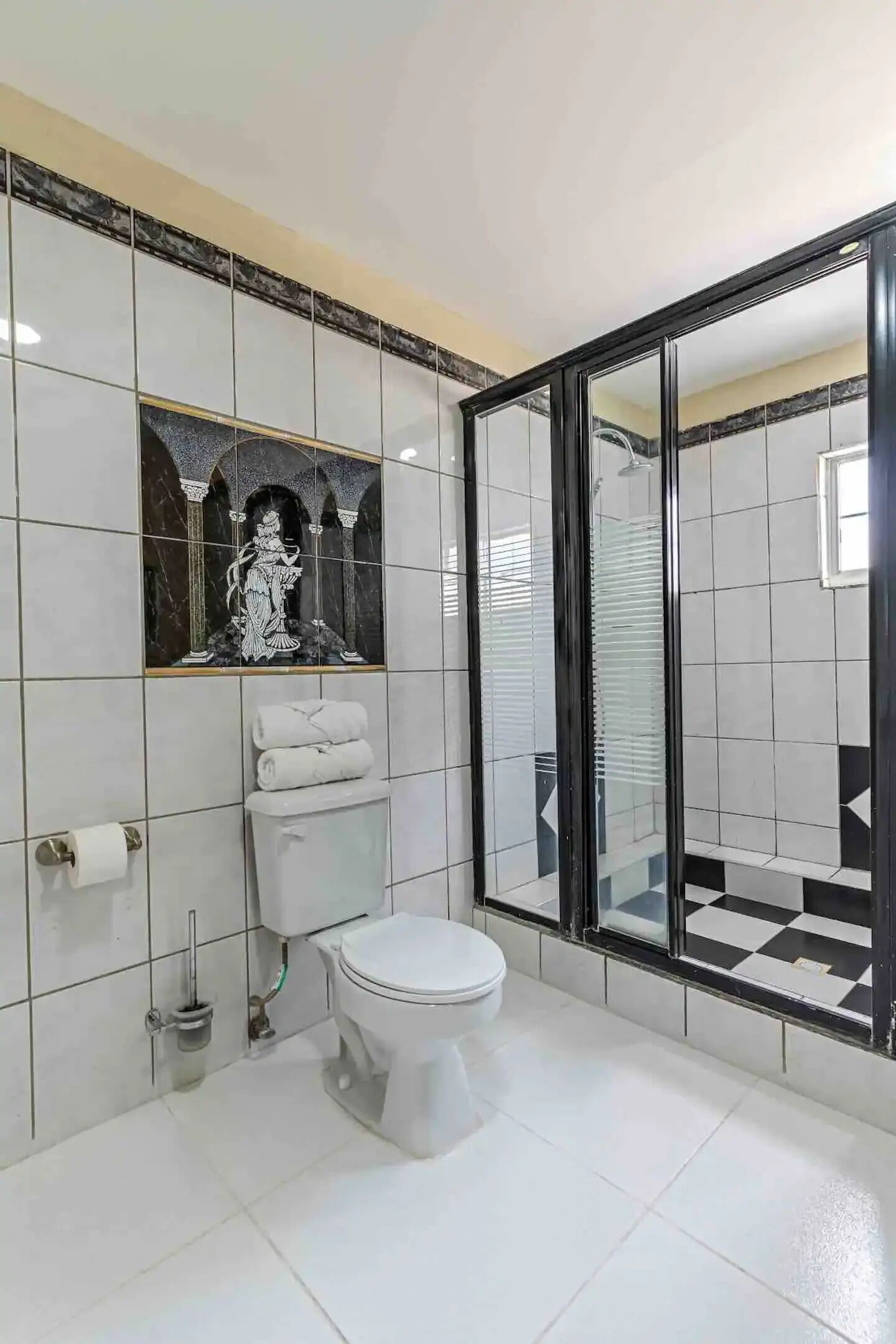 Een badkamer met toilet, bidet, handdoekhouder en een douchecabine van glas.
