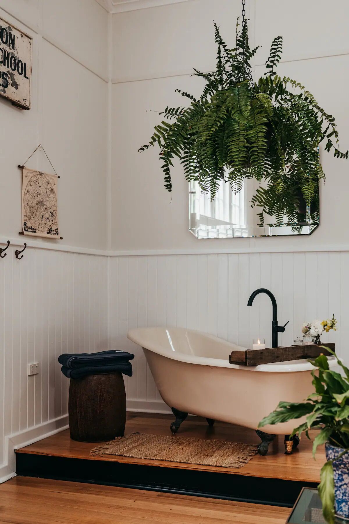 Un baño con una bañera independiente, una planta colgante, un espejo y una ventana pequeña.