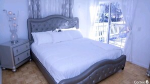 Une chambre à coucher avec un lit, une table de chevet et une fenêtre avec des rideaux.