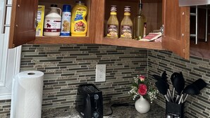 A kitchen with a wooden cabinet containing various food items and condiments. - Charming quiet (Manchester)